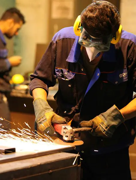 Welder in protective gear grinding steel