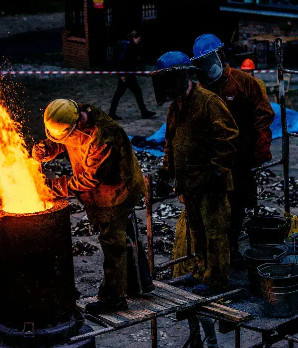 Workers in protective gear at a furnace